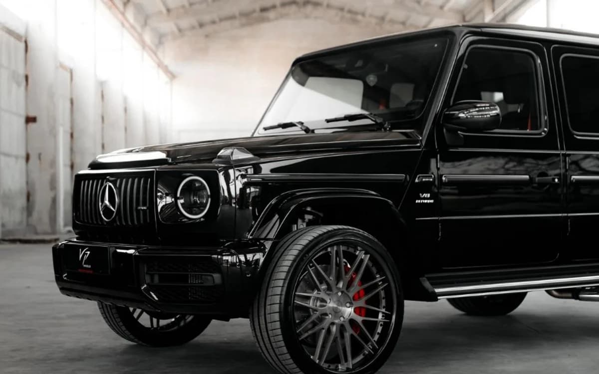 Black Mercedes-AMG G63 luxury SUV with AMG Panamericana grille in a modern warehouse setting