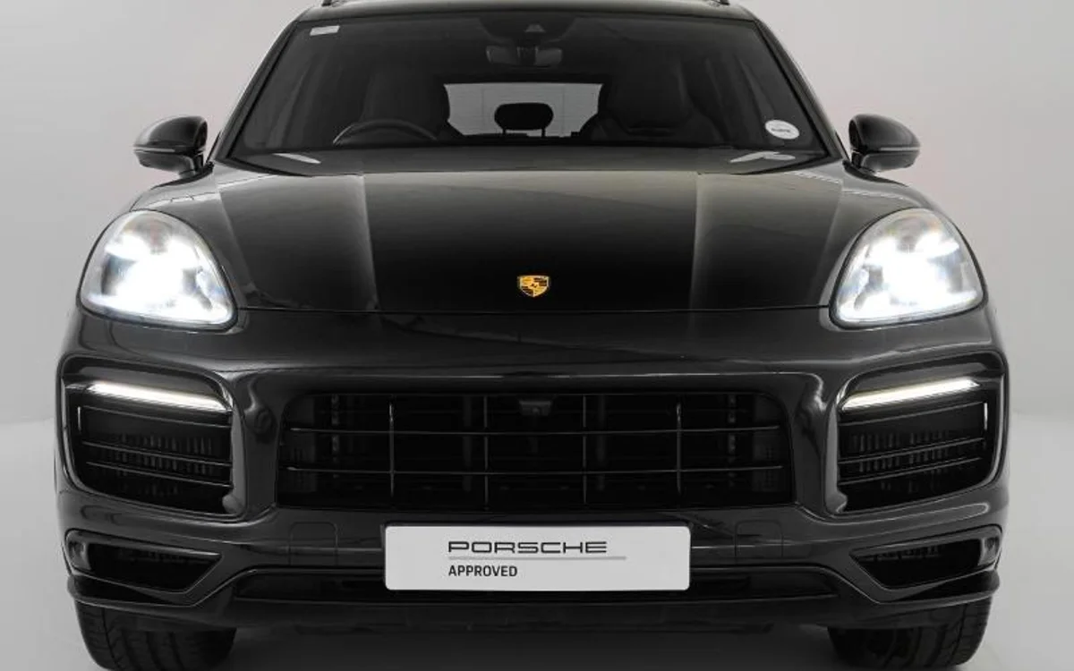 Black Porsche Cayenne SUV with illuminated LED headlights in a studio setting